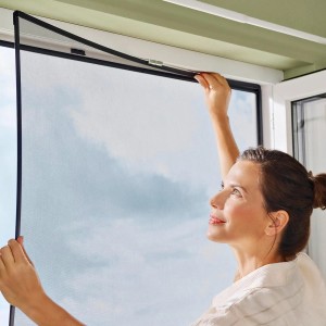 Kobieta montuje ramkę z siatką na owady tesa Insect Stop na oknie.