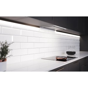 Białe płytki ścienne t.b.t. w nowoczesnej kuchni z płytą grzewczą i okapem.