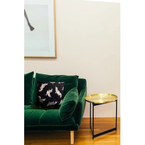 Dekoracyjna poduszka t.b.t. ze wzorem żurawi na zielonej sofie.