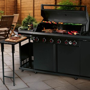 Czarny grill gazowy z jedzeniem i stolikiem na zewnątrz.