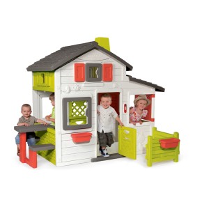 Kolorowy domek do zabawy dla dzieci ze stołem i płotem w ogrodzie.