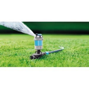 Nawadnianie niebieskim zraszaczem trawnikowym t.b.t. na zielonej trawie.