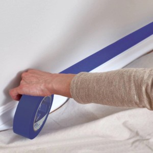 Niebieska taśma malarska t.b.t. naklejana na ścianę i płachtę ochronną.