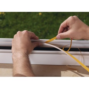 Nakładanie białej piankowej uszczelki okiennej Tesamoll (10 m x 0,9 cm) na ramę okienną.