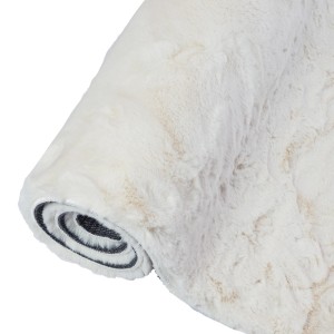 Zrolowany, kremowy dywan z długim włosiem t.b.t. o miękkiej teksturze.