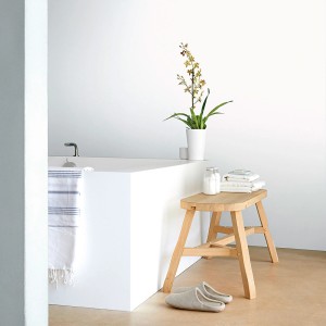 Scena łazienki z wanną, stołkiem, ręcznikami i rośliną.