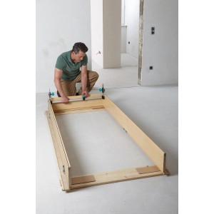 Mężczyzna montuje ościeżnicę za pomocą rozpórki Wolfcraft Easy. Narzędzie zaciskowe do montażu ościeżnic.