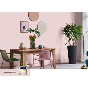 Różowy salon z farbą do ścian Sniezka i drewnianym stołem z dekoracją.