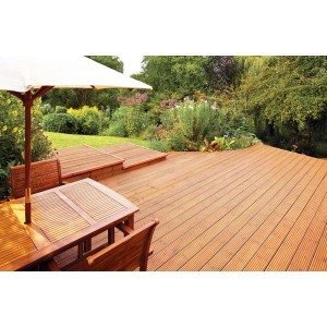 Drewniany taras z meblami ogrodowymi i bujną zielenią, zabezpieczony olejem do drewna.