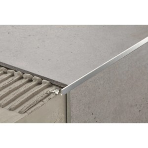 Zbliżenie srebrnego profilu do płytek t.b.t. na szarej płytce.