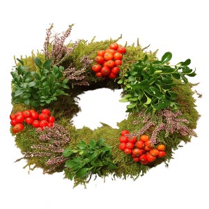 Dekoracyjny wieniec roślinny z mchem, czerwonymi jagodami i zielonymi liśćmi jako roślina doniczkowa.