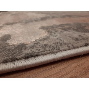 Zbliżenie szarego dywanu z krótkim włosiem i abstrakcyjnym wzorem.