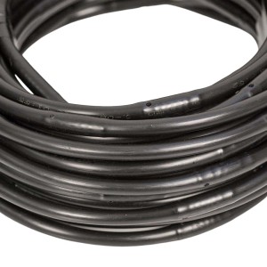 Zwinięty czarny wąż nawadniający t.b.t. do nawadniania podziemnego.