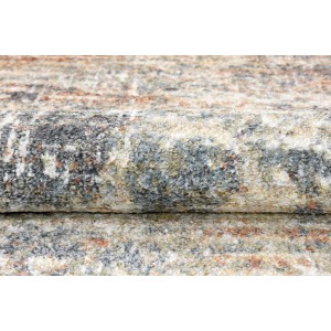 Zbliżenie dywanu z krótkim włosiem o abstrakcyjnym wzorze w odcieniach szarości, beżu i brązu.