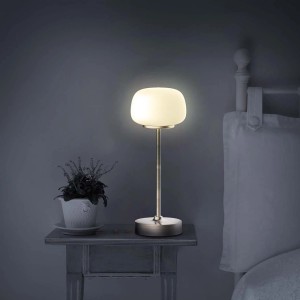 Elegancka lampa stołowa t.b.t. z opalowo białym szklanym kloszem na stoliku nocnym.