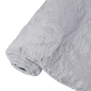 Zrolowany, jasnoszary dywan shaggy t.b.t. o miękkiej fakturze.