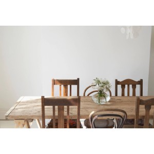 Stół z krzesłami i wazonem z kwiatami na tle białej ściany. Pomysł na aranżację kolorystyczną.