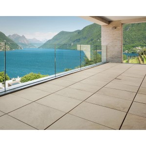 Taras z jasnymi płytami tarasowymi i szklaną balustradą z widokiem na jezioro.