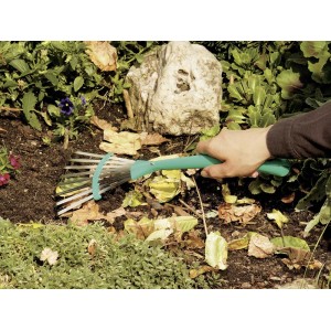Ręczne grabie wachlarzowe LUX Classic w użyciu do grabienia liści na rabacie.
