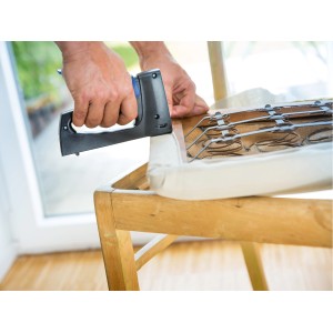 Zszywki z cienkiego drutu: Ręka mocuje tapicerkę do drewnianego krzesła za pomocą zszywek z cienkiego drutu LUX.