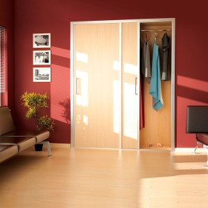 Szafa z drzwiami przesuwnymi i prowadnicami t.b.t., jasny wygląd drewna, częściowo otwarta.