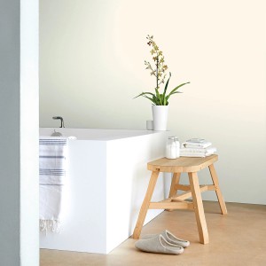 Łazienka z farbą do ścian t.b.t., ozdobiona stołkiem, rośliną i ręcznikami.