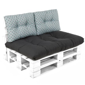 Zestaw mebli ogrodowych t.b.t. z szarą poduszką siedziskową i wzorzystymi poduszkami oparciowymi na białej palecie.