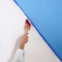 Ręka maluje ścianę na biało pędzlem (t.b.t.). Zamaskowany niebieski obszar.
