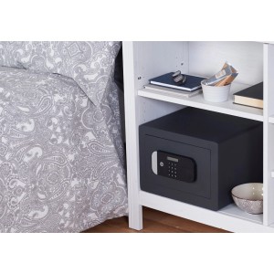 Czarny sejf t.b.t. na białej półce. Kompaktowa konstrukcja z cyfrową klawiaturą.