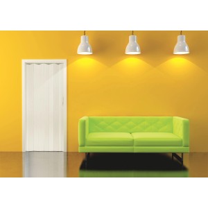 Białe drzwi harmonijkowe na żółtej ścianie, obok zielona sofa. Idealne do małych przestrzeni.