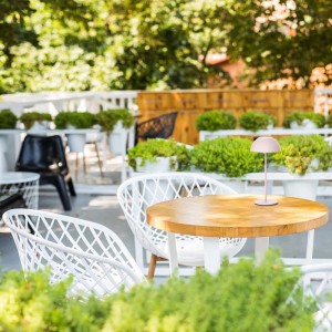 Lampa stołowa t.b.t. na drewnianym stole na zewnątrz. Dekoracyjna lampa do ogrodu lub na taras.