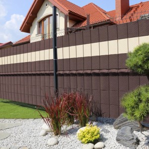 Brązowa i beżowa mata na ogrodzenie t.b.t. zapewniająca prywatność w ogrodzie.