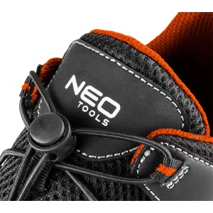 Zbliżenie: Czarny but roboczy t.b.t. z pomarańczowymi akcentami i systemem szybkiego sznurowania.