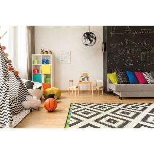 Pokój dziecięcy z lampą wiszącą w kształcie kuli ziemskiej, zabawkami i ścianą tablicową.