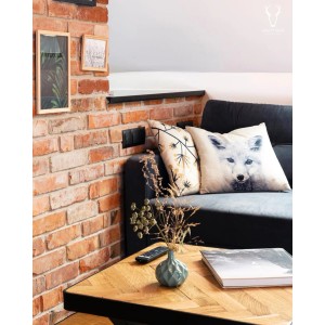 Murowana ściana z poduszkami dekoracyjnymi i stolik z wazonem w salonie.