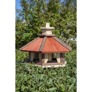 Drewniany karmnik dla ptaków z czerwonym dachem w ogrodzie. Kategoria: Karmniki dla ptaków.