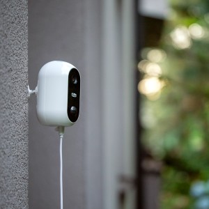 Biała kamera monitoringu t.b.t. zamontowana na ścianie.