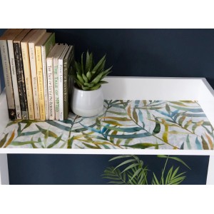 Folia dekoracyjna we wzór liści na stole, obok książek i rośliny.