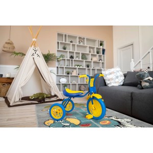 Niebiesko-żółty rowerek trójkołowy dla dzieci na kolorowym dywanie z krótkim włosiem w pokoju dziecięcym.