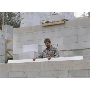 Mężczyzna sprawdza ścianę za pomocą łaty murarskiej LUX 2 m Classic. Aluminiowe narzędzie murarskie z poziomicami.