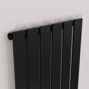 Czarny grzejnik t.b.t. z pionowymi panelami na białej ścianie.