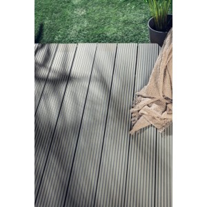 Szare deski tarasowe t.b.t. z ręcznikiem na tarasie w ogrodzie.