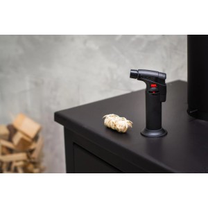 Czarny palnik gazowy (lutownica) z rozpałką na czarnym stole.