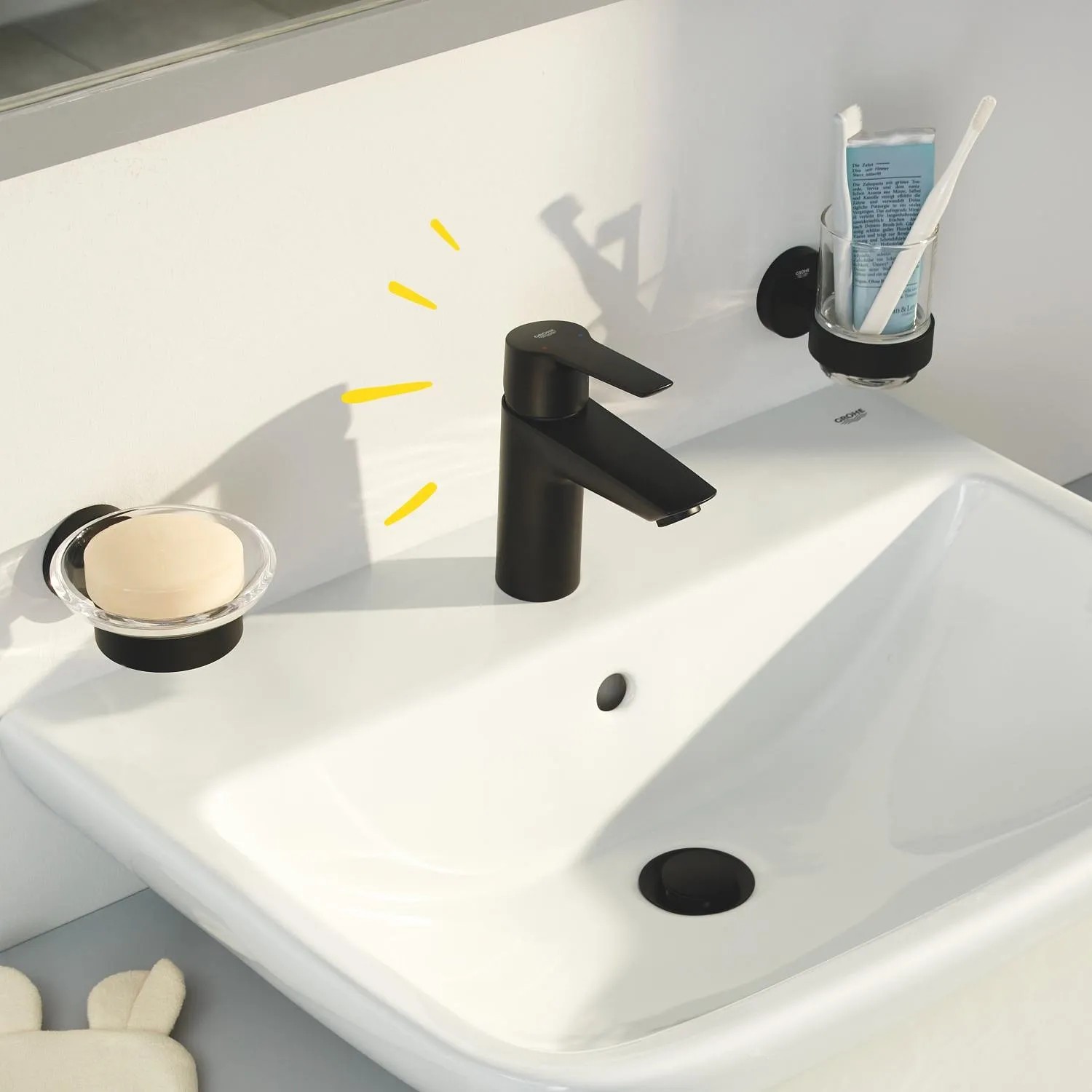Czarna bateria umywalkowa Grohe QuickFix Start S-Size na białej umywalce z mydłem i szczoteczką do zębów.
