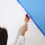 Ręka maluje ścianę czerwonym pędzlem (t.b.t.) i niebieską farbą. Kategoria: Pędzle.