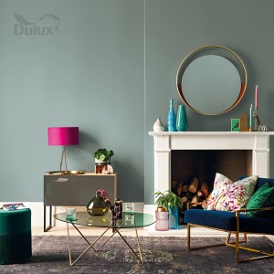 Salon w stonowanej zieleni z kominkiem, meblami i elementami dekoracyjnymi. Kolorowa farba do ścian dla przytulnej atmosfery.