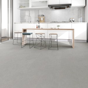 Jasne oświetlony pokój z szarymi panelami winylowymi. Widok na nowoczesną kuchnię z stołkami barowymi.