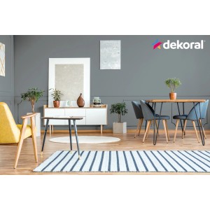 Szary salon z farbą do ścian Dekoral, żółtym fotelem i stołem jadalnym.