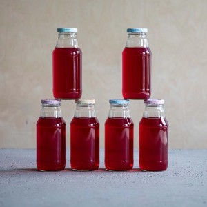 Siedem butelek czerwonego soku, ułożonych w stos. Kategoria: Winiarstwo i przetwórstwo.