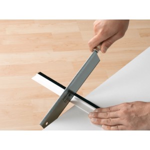 Przycinanie białej uszczelki do drzwi Tesamoll Comfort do nierównych podłóg za pomocą piły.